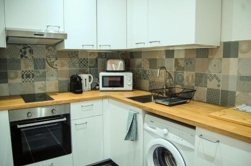 une cuisine avec des armoires blanches et un micro-ondes dans l'établissement POISSY Appartements COSY, à Poissy