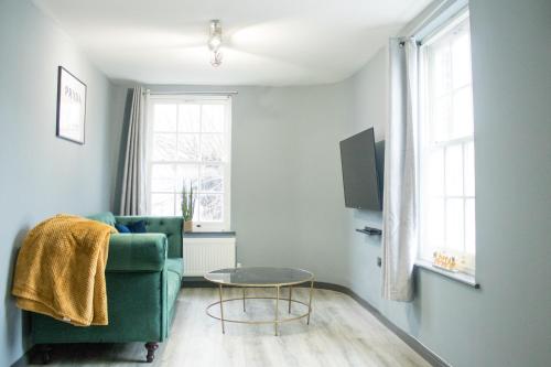 a living room with a green couch and a table at The Countryman Hideaway - Funky Loft Room in Gillingham
