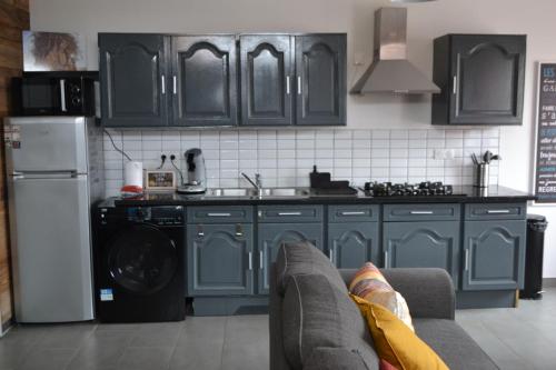 La cuisine est équipée de placards bleus et d'un four avec plaques de cuisson. dans l'établissement Cosy home du Hameau, à Merckeghem