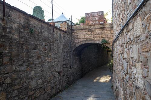 an alley with a stone wall and a tunnel at old medieval apartment in San Donato in Poggio