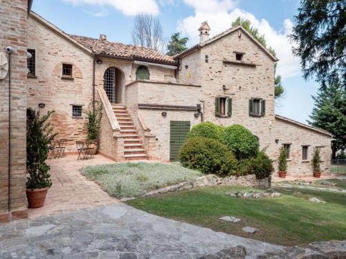 an external view of a large stone house with a patio at Apartment in Villagrande with Pool & Garden in Mombaroccio