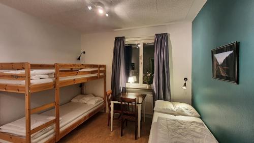 a bedroom with two bunk beds and a table and a desk at Virserum Hostel in Virserum