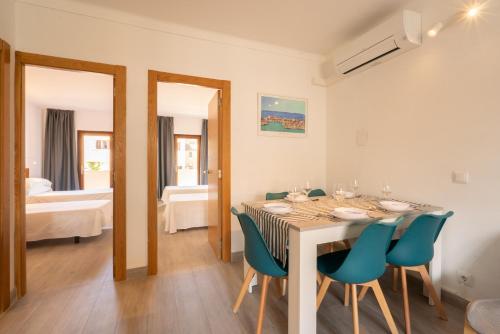 a dining room with a table and blue chairs at Apartamentos Estanques in Colonia Sant Jordi