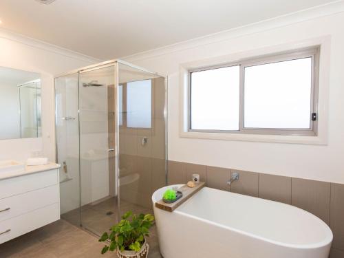 a bathroom with a tub and a glass shower at Jindalee 3 34 Twynam St in Jindabyne