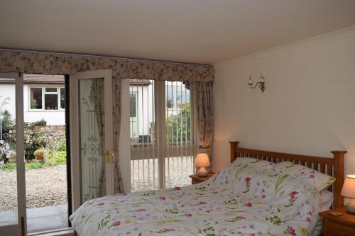 um quarto com uma cama e uma porta de vidro deslizante em Sandhurst Farm Forge Self Catering Stableblock em Sittingbourne