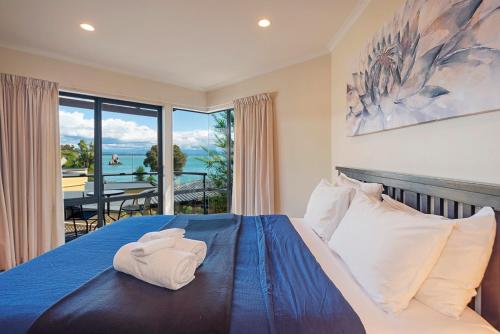 a bedroom with a blue bed with a view of the ocean at On The Rocks in Nelson