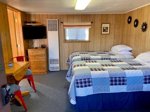 a bedroom with two beds and a desk and a television at Betsie Riverside Resort in Benzonia