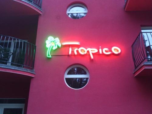 a pink building with a neon sign on it at Villa Tropico śniadanie i obiadokolacja in Pobierowo