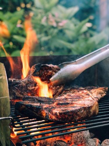 a steak being grilled on a grill with a spatula at Tops10 Resort Donggang Cistar in Yeongwol