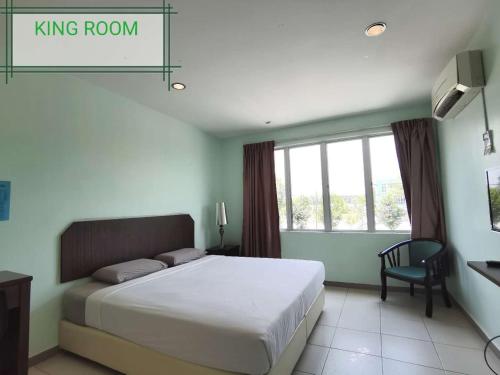 a bedroom with a king room with a bed and a chair at GS BERA HOTEL SDN BHD in Kampong Kerayong