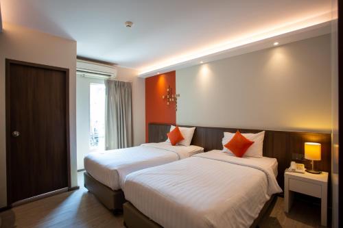 Lemontea Hotel Bangkok - SHA Extra Plus في بانكوك: سريرين في غرفة الفندق بجدران برتقالية