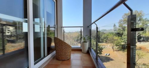 a balcony with glass doors and chairs and a view at Golden Healing Journeys Homestay in Rishīkesh