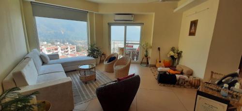 a living room with a couch and a large window at Golden Healing Journeys Homestay in Rishīkesh