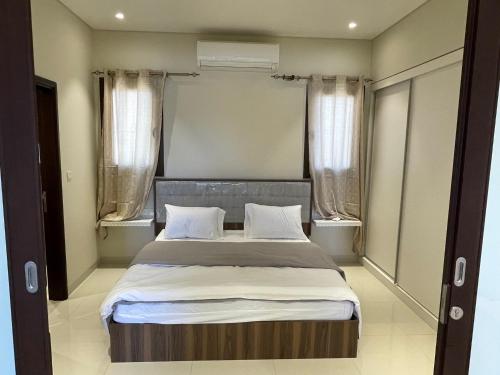 Mokango Apartment Hawana Salalah في صلالة: غرفة نوم بسرير كبير مع نافذتين