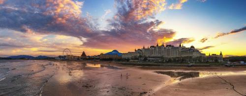 a large building on the beach with a sunset at Crowne Plaza Ocean Spring Resort by IHG in Jimo