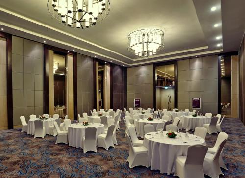 a banquet hall with white tables and chairs and chandeliers at Mercure Serpong Alam Sutera in Serpong