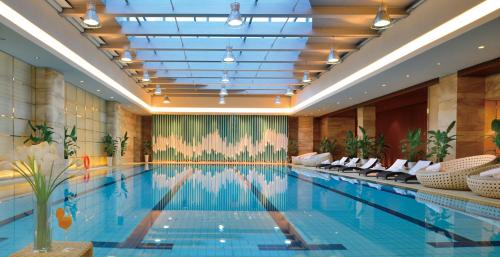 une grande piscine dans un hôtel avec des chaises dans l'établissement Crowne Plaza Dalian Sports Center, an IHG Hotel, à Dalian