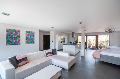 a living room with white couches and a kitchen at VV hotel & apartments in Brno