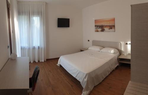 a bedroom with a white bed and a television at LOCANDA L'OFFICINA in Ceggia