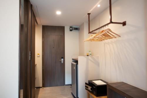 a room with a white wall and a wooden door at Lemontea Hotel Bangkok in Bangkok
