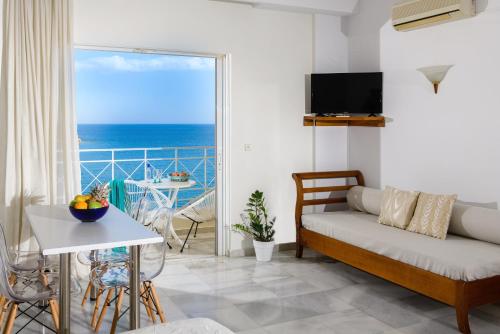 een woonkamer met een bank en uitzicht op de oceaan bij Bellevue Suites in Agios Nikolaos