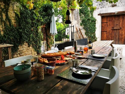 una mesa de madera con comida en el patio en Le Bonheur- Suite Cognac en Hiersac