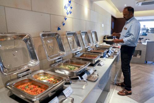 a man standing in front of a buffet of food at Royal Orchid Golden Suites Pune in Pune
