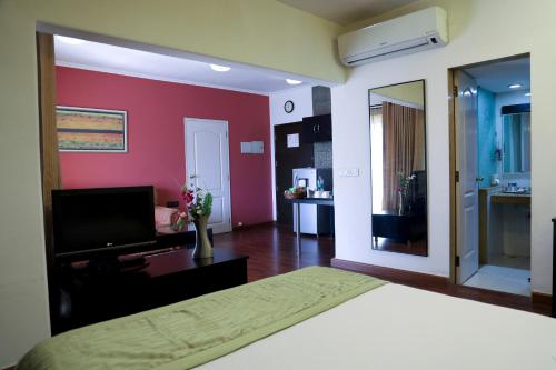 a bedroom with a bed and a television and a bathroom at Royal Orchid Golden Suites Pune in Pune