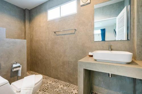 a bathroom with a sink and a toilet and a mirror at Bianco House Resort in Cha Am