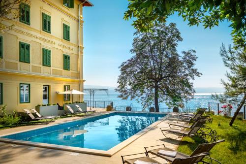 basen z leżakami obok budynku w obiekcie Apartments Belvedere - Liburnia w mieście Lovran