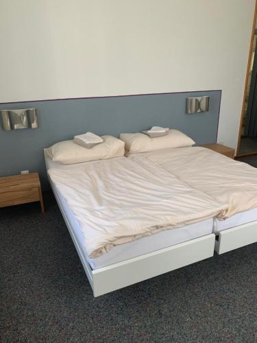 Una cama con sábanas blancas y almohadas. en Hôtel Maison Blanche, en Yverdon-les-Bains