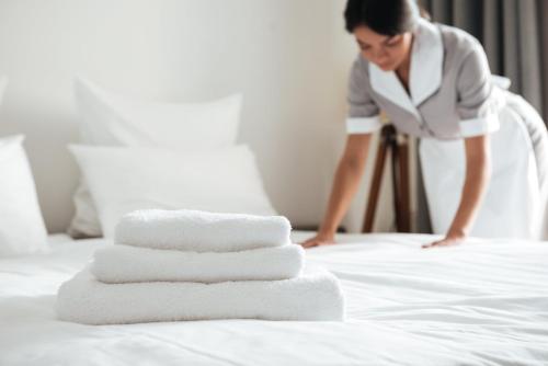 a woman cleaning a bed with four towels at Boutique Hotel O. Galogre in Batumi