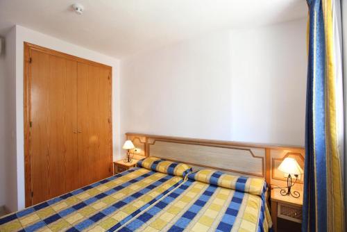 a bedroom with a bed with a blue and yellow checkered blanket at Apartamentos Benimar - SABESA in Benidorm