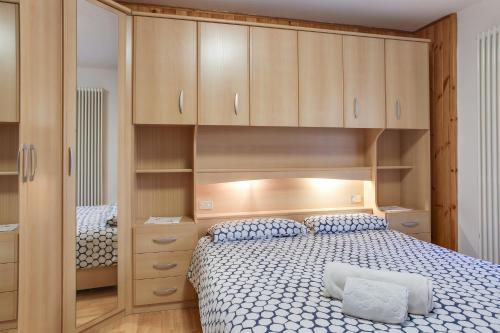 1 dormitorio con 1 cama y armarios de madera en Casa March 1, en Moena