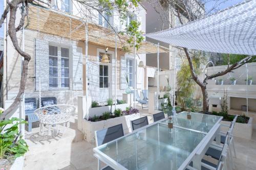 a patio with a glass table and chairs in front of a building at La Maison de Famille 3 chambres 8 pers Terrasse Parking Clim in Marseille