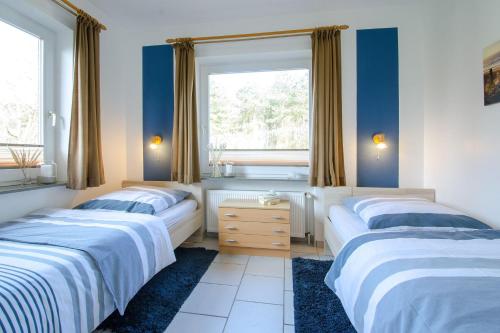 two beds in a bedroom with blue walls and a window at App-1-Alkersum in St. Peter-Ording