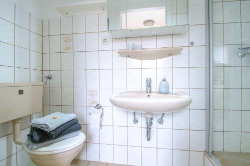 a white bathroom with a sink and a toilet at App-1-Alkersum in St. Peter-Ording