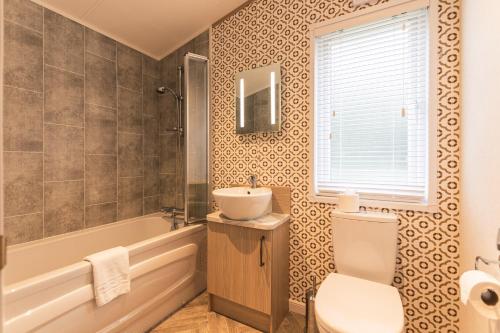 a bathroom with a sink and a tub and a toilet at Hemingway Lodge with Hot Tub in York