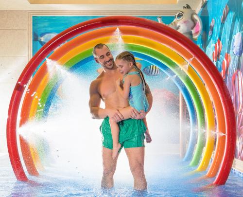 a man and a woman standing under a rainbow in a water park at Park & Spa Hotel Markovo in Plovdiv