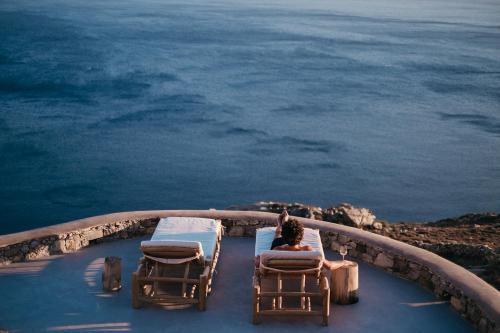 a woman sitting in chairs on a balcony looking at the ocean at Pénde Natura Residences in Rámos