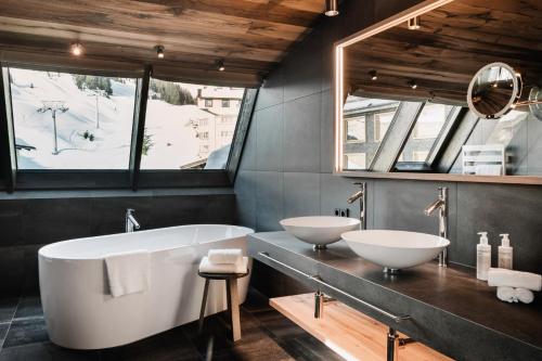a bathroom with two sinks and a bath tub at Berghotel Biberkopf in Warth am Arlberg