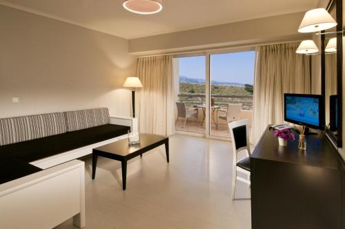 a living room with a couch and a table and a television at Kipriotis Panorama Hotel & Suites in Kos Town