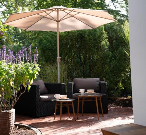a patio with two chairs and an umbrella at Studio-Apartment Piccolino 26 in Timmendorfer Strand