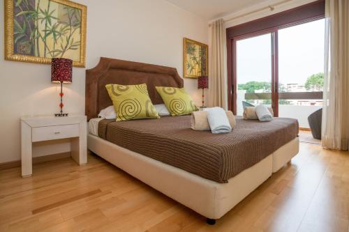 um quarto com uma cama e uma grande janela em Modern Vila Sol Townhouse with Traditional Vibes em Quarteira