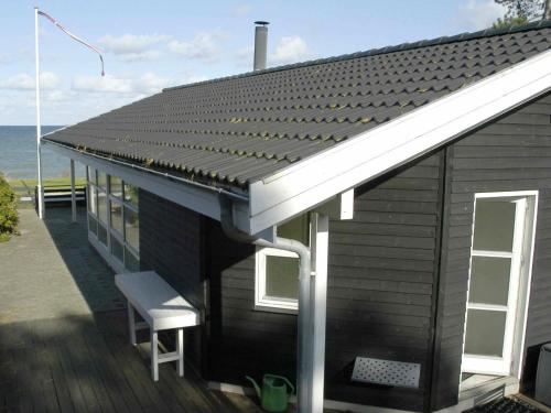 ein Haus mit einem Dach mit einer Bank auf einem Deck in der Unterkunft 4 person holiday home in Otterup in Otterup