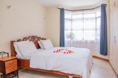 a bedroom with a bed with white sheets and a window at JKIA homestays in Nairobi