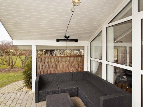 a screened in porch with a black couch at 8 person holiday home in Hemmet in Hemmet