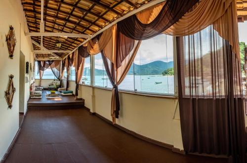 a room with a large window with a view of the water at Pousada Sobre As Ondas de Picinguaba in Picinguaba