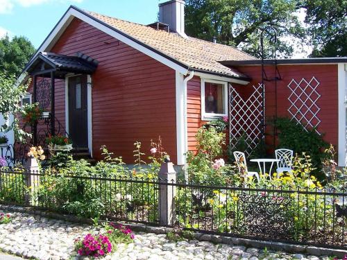 una pequeña casa roja con una valla y flores en 5 person holiday home in H SSLEHOLM, en Hässleholm