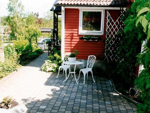 a patio with two chairs and a table in front of a red house at 5 person holiday home in H SSLEHOLM in Hässleholm